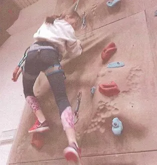 Malá lezkyně na boulderingové stěně
