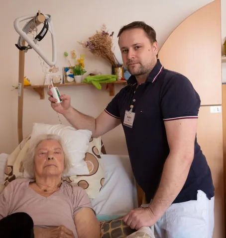 Pečovatel u nového polohovacího lůžka klientky domova Sue Ryder