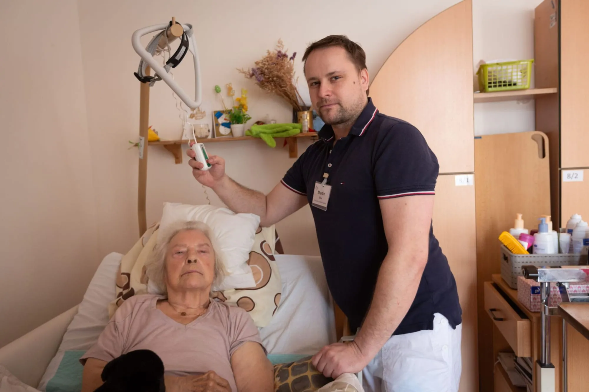 Pečovatel u nového polohovacího lůžka klientky domova Sue Ryder